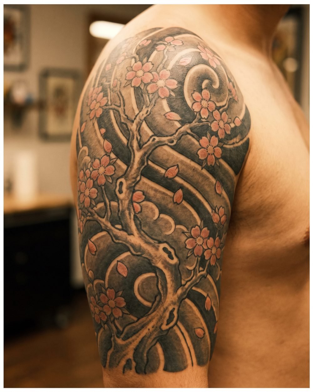 Irezumi style cherry blossom branch tattoo with bold outlines on an upper arm