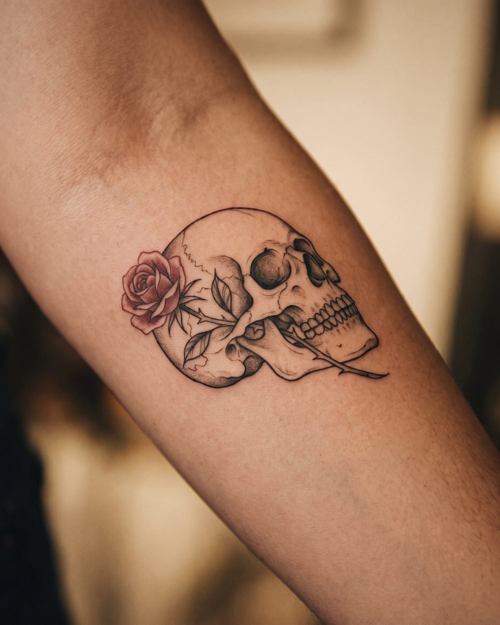 Memento mori tattoo of a skull with a rose beside it in fine-line detail