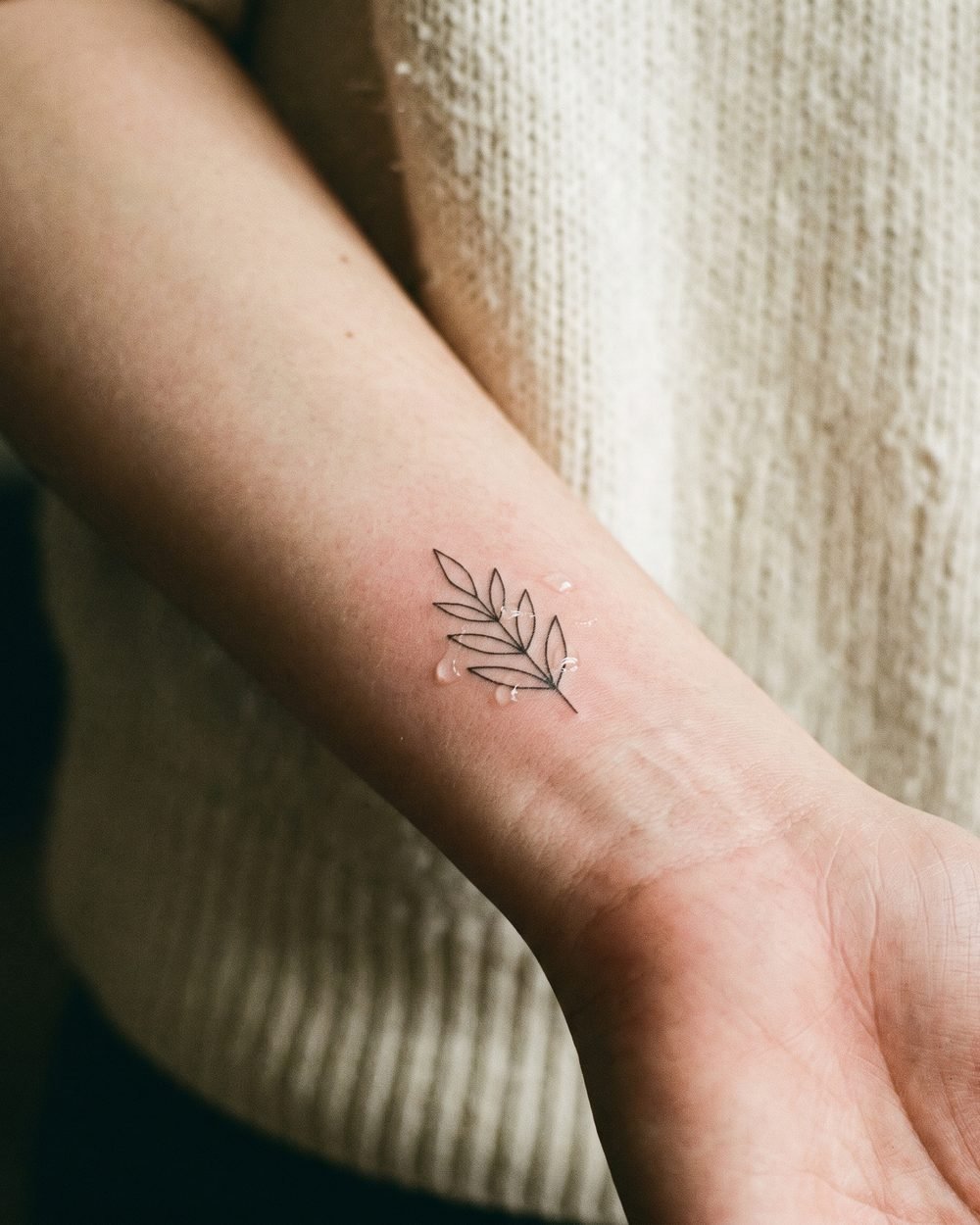A small fresh fine-line tattoo on a forearm
